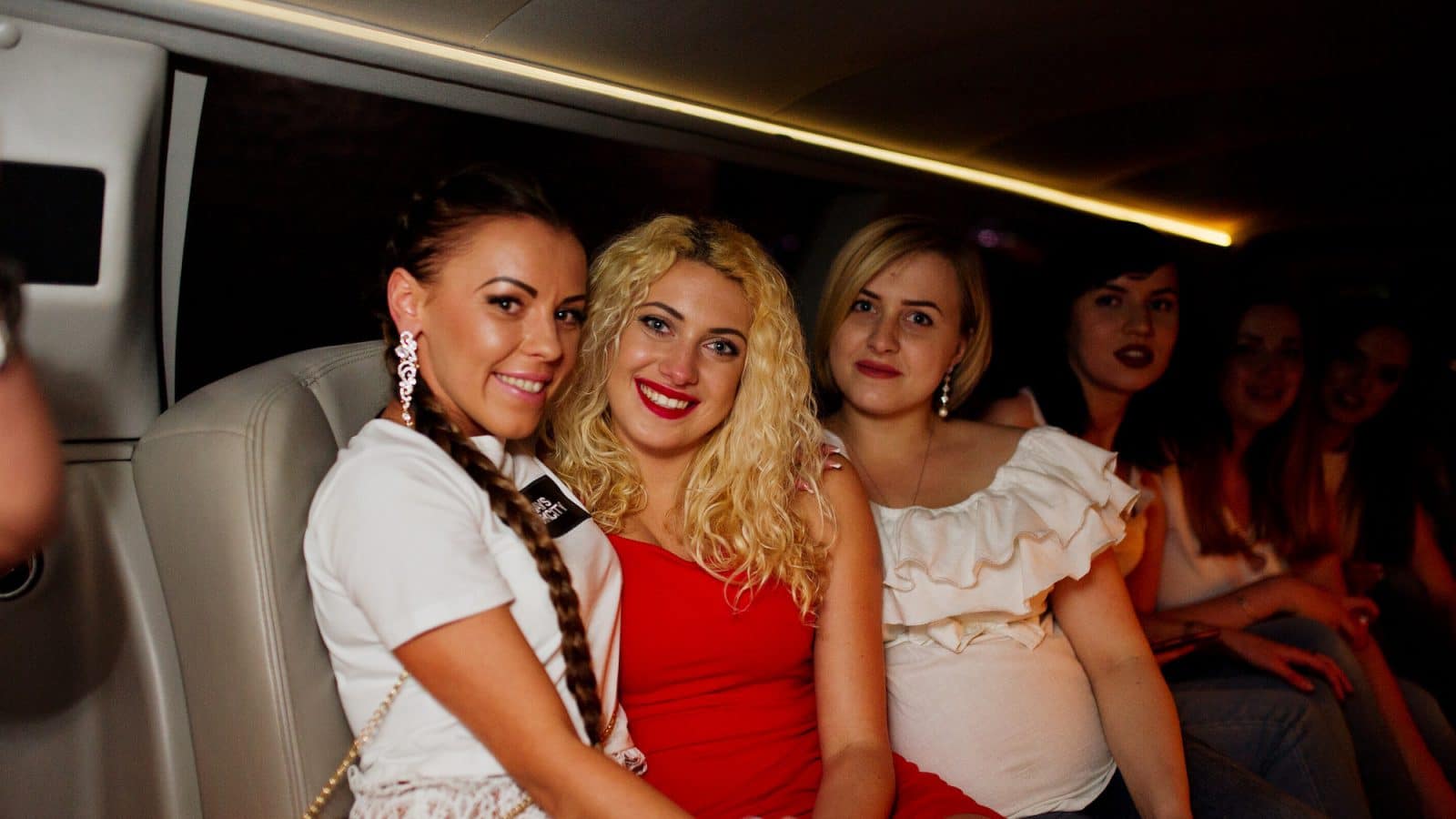 Gorgeous girls having fun while sitting inside the luxurious limousin at bachelorette party.